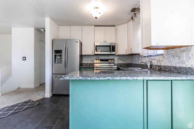 4287 W Stratus S, Kearns, UT 84118 - kitchen with appliances with stainless steel finishes, decorative backsplash, white cabinets, dark stone counters, and a peninsula