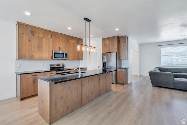 514 S 900 W Unit 167, American Fork, UT 84003 - kitchen featuring stainless steel appliances, dark countertops, light wood-style floors, a center island with sink, and decorative backsplash