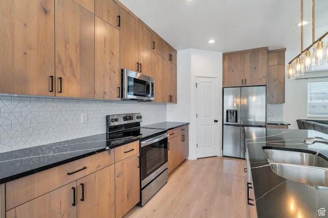 514 S 900 W Unit 167, American Fork, UT 84003 - kitchen with appliances with stainless steel finishes, light wood finished floors, tasteful backsplash, dark stone countertops, and decorative light fixtures