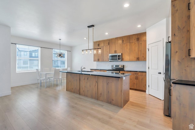 514 S 900 W Unit 167, American Fork, UT 84003 - kitchen with appliances with stainless steel finishes, dark countertops, decorative backsplash, a center island with sink, and light wood-style flooring