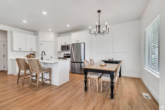1162 N 550 W Unit 110, Tooele, UT 84074 - kitchen featuring appliances with stainless steel finishes, light wood finished floors, a chandelier, white cabinets, and recessed lighting