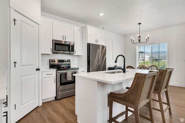 1162 N 550 W Unit 110, Tooele, UT 84074 - kitchen with appliances with stainless steel finishes, a chandelier, light wood-style floors, a kitchen breakfast bar, and recessed lighting