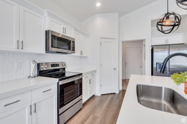 7194 N Clear Meadow Way, Eagle Mountain, UT 84005 - kitchen with stainless steel appliances, light countertops, white cabinetry, light wood-style flooring, and decorative backsplash
