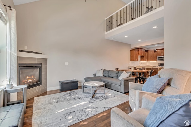 7162 S Beamon St W, West Jordan, UT 84084 - living room featuring dark wood-type flooring, a high ceiling, a fireplace, and recessed lighting