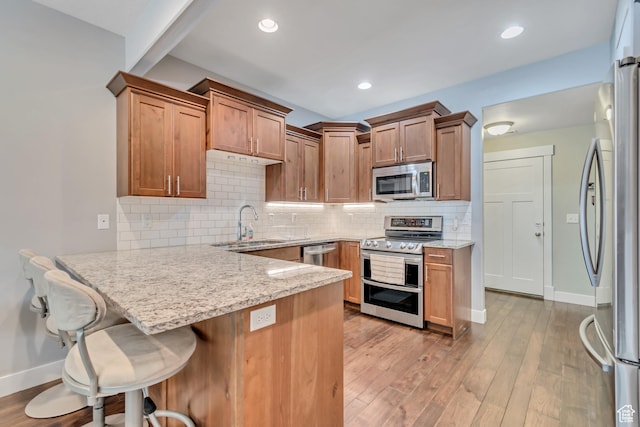 7162 S Beamon St W, West Jordan, UT 84084 - kitchen featuring appliances with stainless steel finishes, a peninsula, light stone countertops, light wood finished floors, and recessed lighting