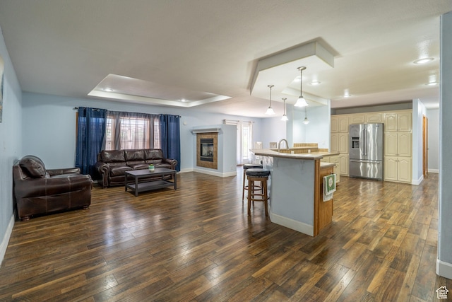 975 S 400 E, Moab, UT 84532 - kitchen with stainless steel fridge with ice dispenser, open floor plan, a breakfast bar area, a kitchen island with sink, and a raised ceiling