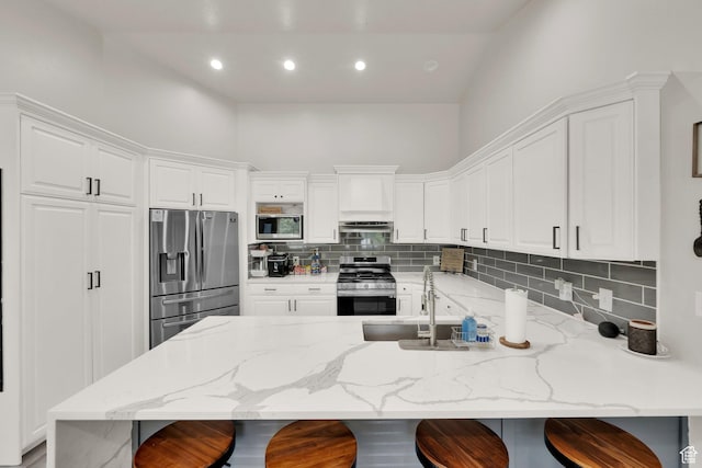 1569 Troon Cir, Syracuse, UT 84075 - kitchen featuring appliances with stainless steel finishes, tasteful backsplash, a peninsula, white cabinets, and recessed lighting