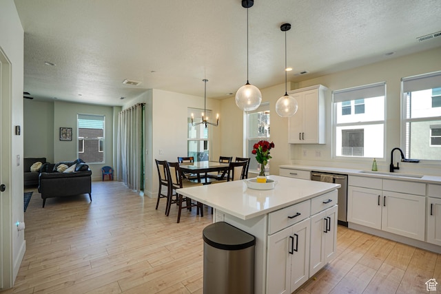 604 N Sego Way Unit 207, Farmington, UT 84025 - kitchen with dishwasher, light wood-style flooring, a center island, a chandelier, and a textured ceiling