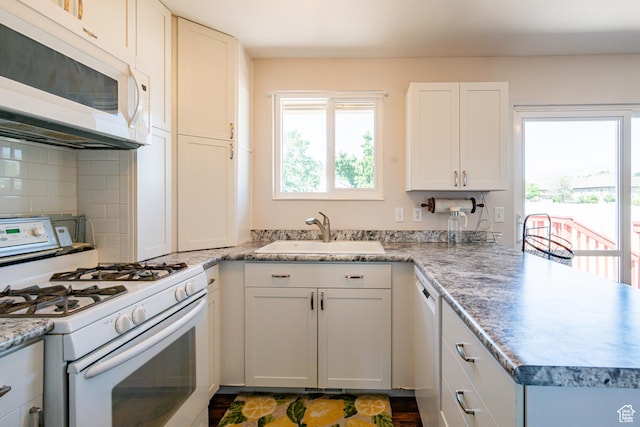 991 E Sunburn Ln, Sandy, UT 84094 - kitchen with white appliances, healthy amount of natural light, backsplash, and a peninsula