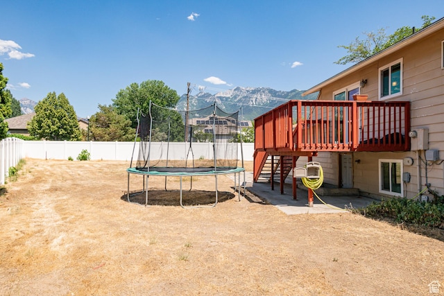 991 E Sunburn Ln, Sandy, UT 84094 - view of playground featuring a trampoline, stairway, a deck with mountain view, and a fenced backyard