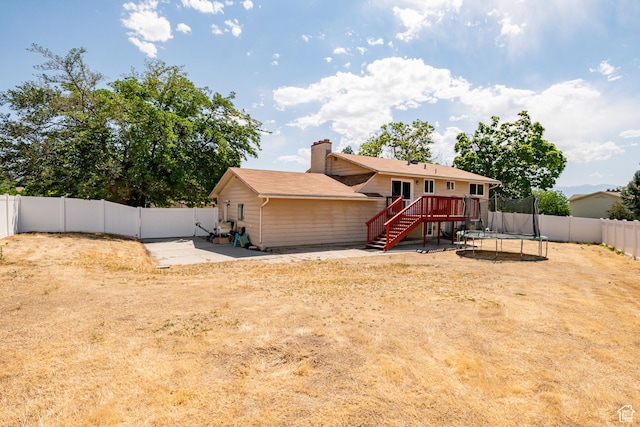 991 E Sunburn Ln, Sandy, UT 84094 - back of property with stairway, a trampoline, a fenced backyard, a deck, and a chimney