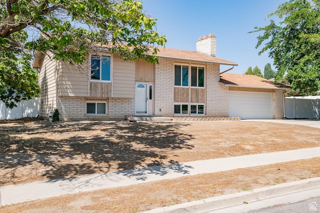 991 E Sunburn Ln, Sandy, UT 84094 - bi-level home featuring a chimney, brick siding, driveway, and an attached garage