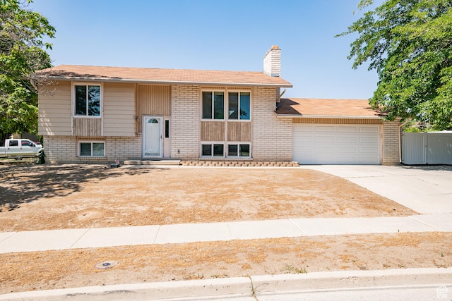 991 E Sunburn Ln, Sandy, UT 84094 - bi-level home featuring a chimney, a garage, driveway, and brick siding