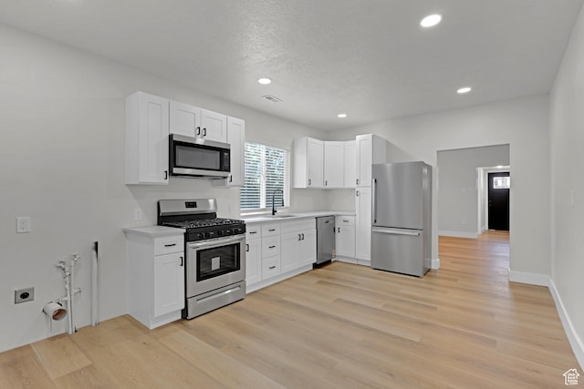2136 Union Ave, Ogden, UT 84401 - kitchen featuring appliances with stainless steel finishes, light countertops, white cabinets, light wood-style floors, and recessed lighting