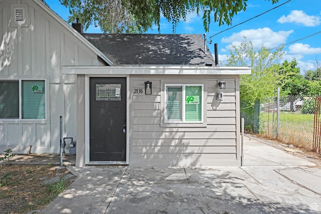 2136 Union Ave, Ogden, UT 84401 - view of exterior entry with board and batten siding, a shingled roof, a patio area, and a chimney