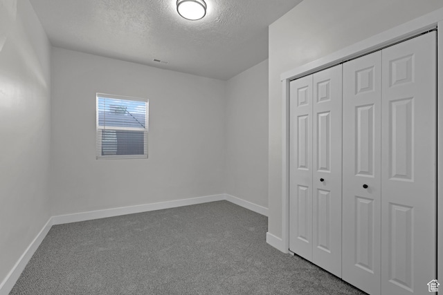 2136 Union Ave, Ogden, UT 84401 - unfurnished bedroom featuring a textured ceiling, dark colored carpet, and a closet