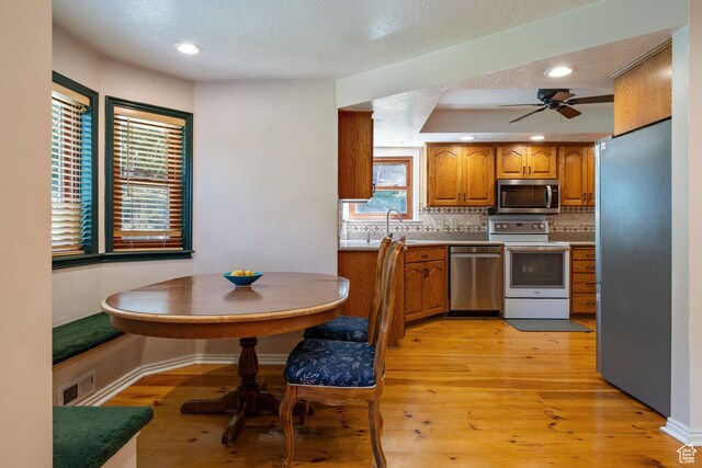 610 S Maple Dr, Woodland Hills, UT 84653 - kitchen with appliances with stainless steel finishes, brown cabinets, decorative backsplash, ceiling fan, and light wood finished floors