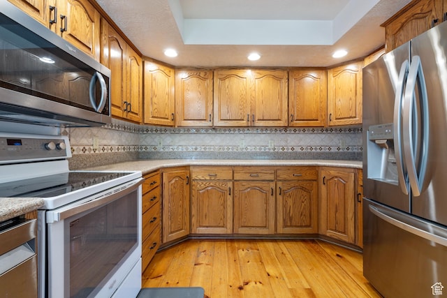 610 S Maple Dr, Woodland Hills, UT 84653 - kitchen with stainless steel appliances, brown cabinetry, light wood-style floors, a raised ceiling, and recessed lighting