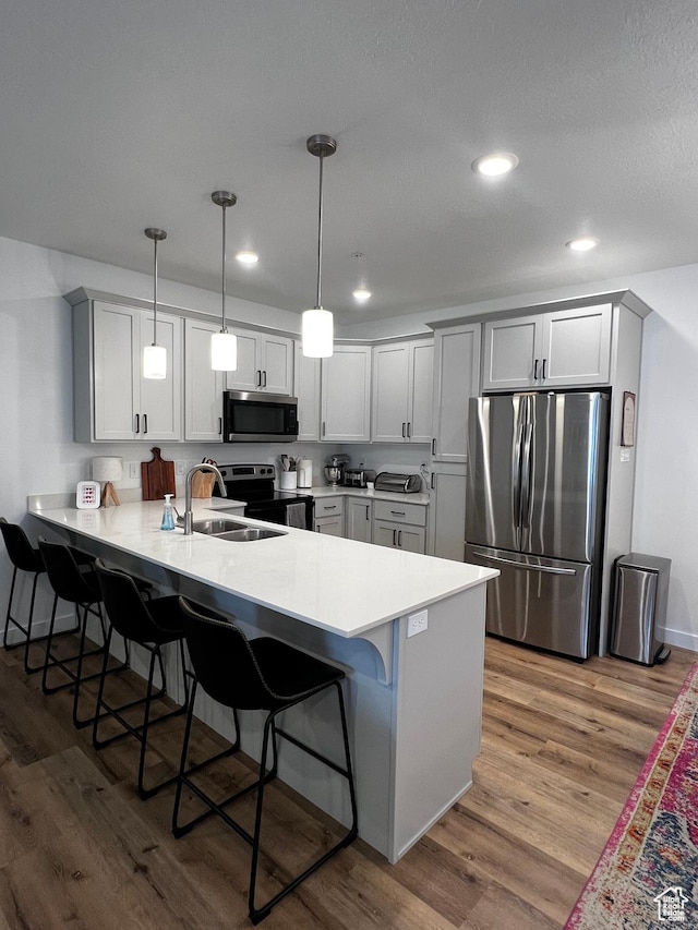 2342 E 830 S Unit 26, Spanish Fork, UT 84660 - kitchen featuring stainless steel appliances, a peninsula, a breakfast bar, wood finished floors, and recessed lighting