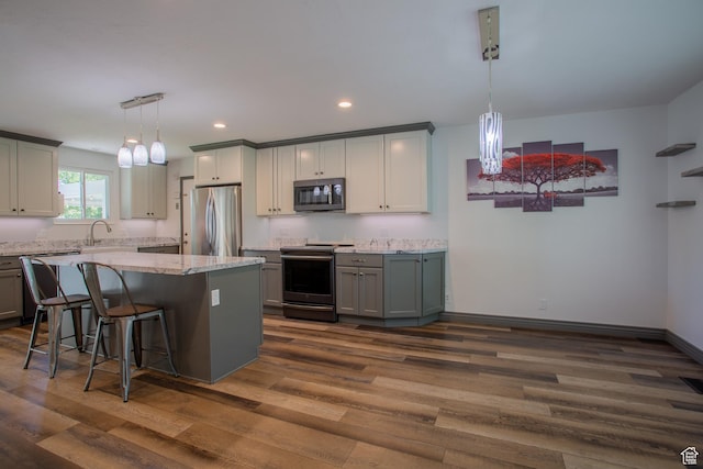 5183 W Cadenza Dr, West Jordan, UT 84081 - kitchen with stainless steel appliances, dark wood-style flooring, gray cabinets, light stone countertops, and a breakfast bar area
