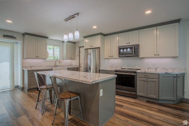 5183 W Cadenza Dr, West Jordan, UT 84081 - kitchen with appliances with stainless steel finishes, gray cabinets, dark wood-type flooring, a breakfast bar area, and a center island