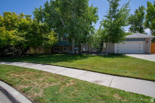 5183 W Cadenza Dr, West Jordan, UT 84081 - view of property hidden behind natural elements featuring brick siding, an attached garage, and driveway