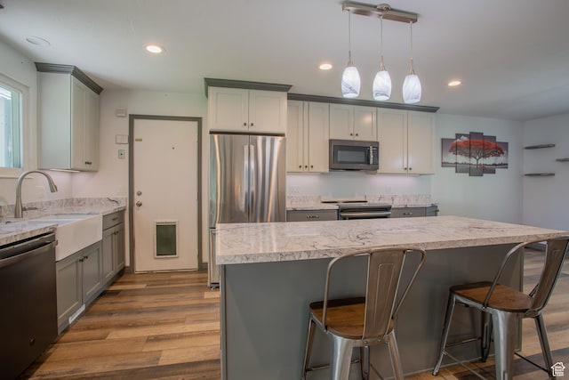 5183 W Cadenza Dr, West Jordan, UT 84081 - kitchen with appliances with stainless steel finishes, gray cabinetry, wood finished floors, a breakfast bar, and recessed lighting