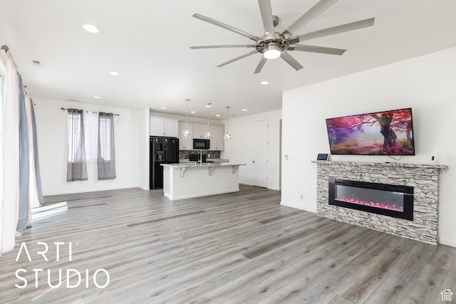 5241 S 1250 W, Riverdale, UT 84405 - unfurnished living room featuring light wood finished floors, a ceiling fan, recessed lighting, and a stone fireplace