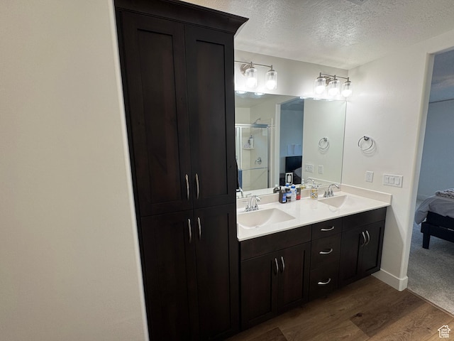 503 S Stewart Creek Cv, Washington, UT 84780 - ensuite bathroom with double vanity, a textured ceiling, a shower stall, and wood finished floors