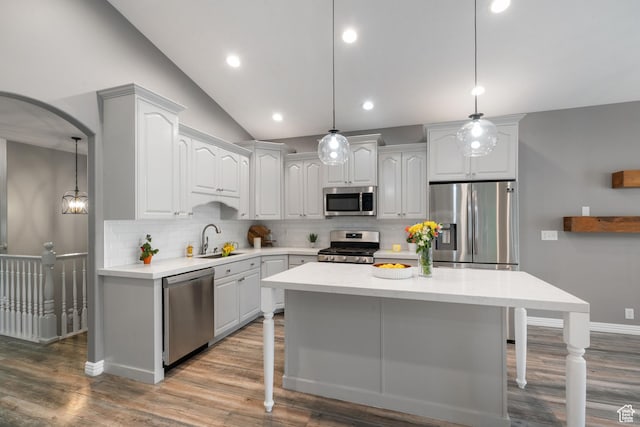 311 E Edgemont Dr S, North Salt Lake, UT 84054 - kitchen with appliances with stainless steel finishes, a kitchen breakfast bar, decorative backsplash, wood finished floors, and vaulted ceiling