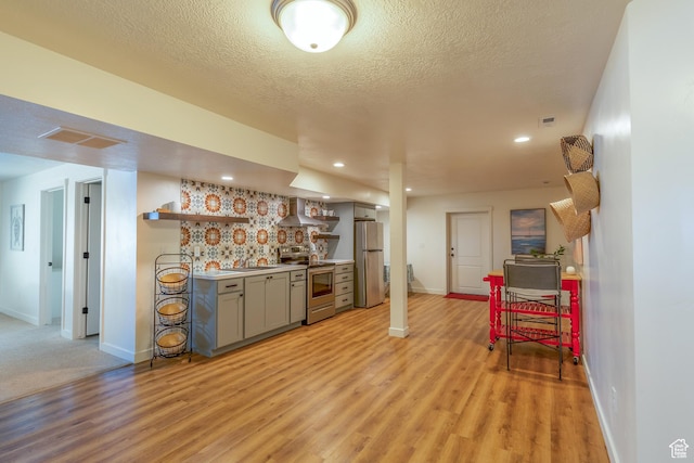 69 W 2200 S, Kaysville, UT 84037 - kitchen with stainless steel appliances, open shelves, wall chimney exhaust hood, gray cabinetry, and light wood finished floors