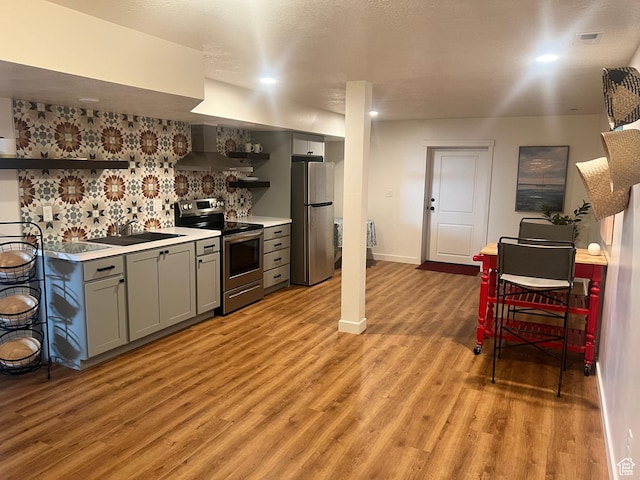 69 W 2200 S, Kaysville, UT 84037 - kitchen with stainless steel appliances, open shelves, wall chimney exhaust hood, gray cabinetry, and light wood-style flooring
