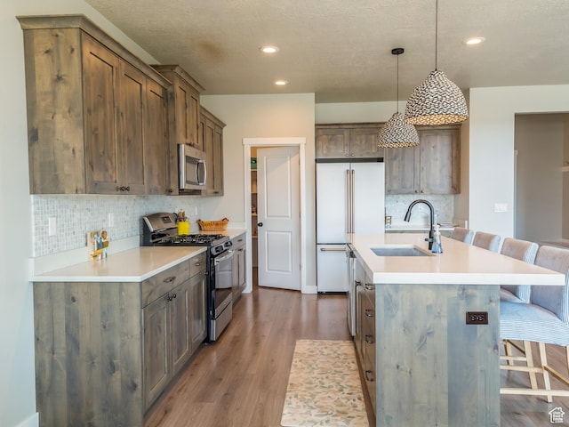 69 W 2200 S, Kaysville, UT 84037 - kitchen with appliances with stainless steel finishes, a breakfast bar, backsplash, wood finished floors, and a center island with sink