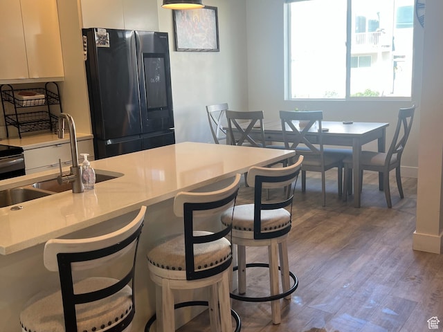 3589 S Xenon Dr W, West Valley City, UT 84119 - kitchen featuring smart refrigerator, white cabinets, a breakfast bar, light countertops, and wood finished floors