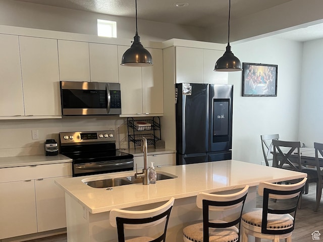 3589 S Xenon Dr W, West Valley City, UT 84119 - kitchen featuring appliances with stainless steel finishes, a breakfast bar, white cabinetry, and pendant lighting