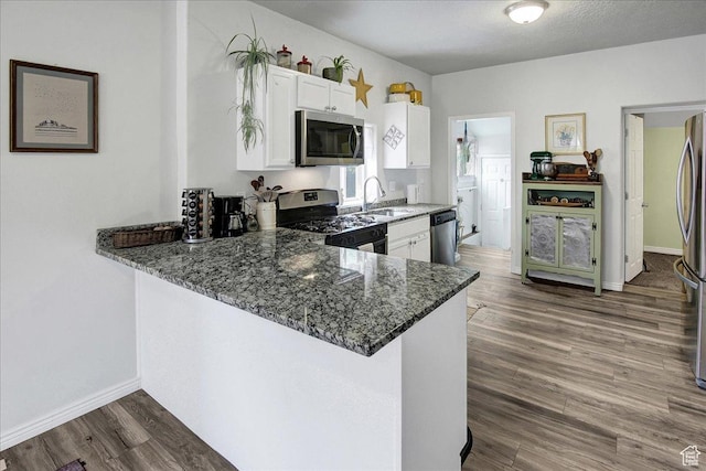 3241 Grant Ave, Ogden, UT 84401 - kitchen featuring appliances with stainless steel finishes, dark stone counters, white cabinets, dark wood-type flooring, and a peninsula