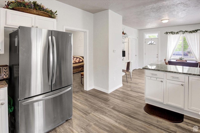 3241 Grant Ave, Ogden, UT 84401 - kitchen featuring freestanding refrigerator, stone countertops, white cabinets, light wood finished floors, and a textured ceiling