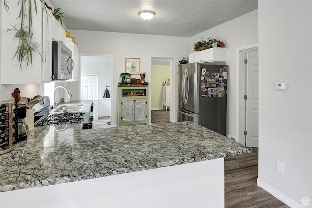 3241 Grant Ave, Ogden, UT 84401 - kitchen with appliances with stainless steel finishes, light stone countertops, white cabinets, a peninsula, and a textured ceiling
