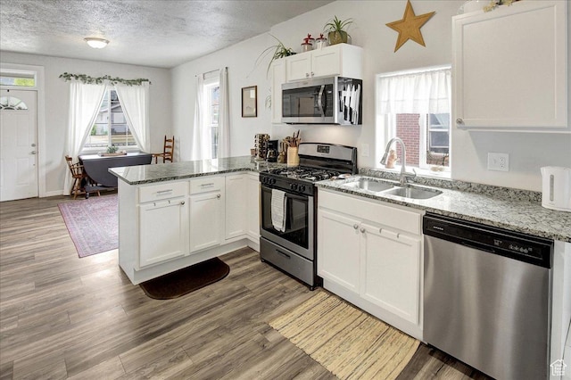 3241 Grant Ave, Ogden, UT 84401 - kitchen with stainless steel appliances, a peninsula, a textured ceiling, white cabinets, and light wood-style flooring