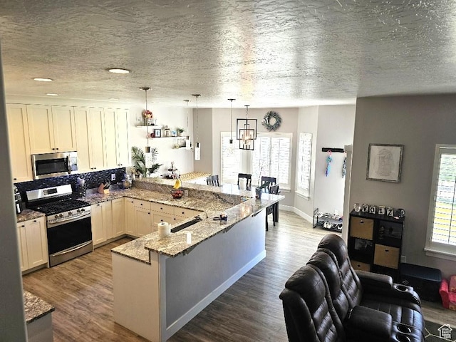 826 S 300 W, Vernal, UT 84078 - kitchen featuring appliances with stainless steel finishes, a peninsula, plenty of natural light, light stone counters, and a textured ceiling