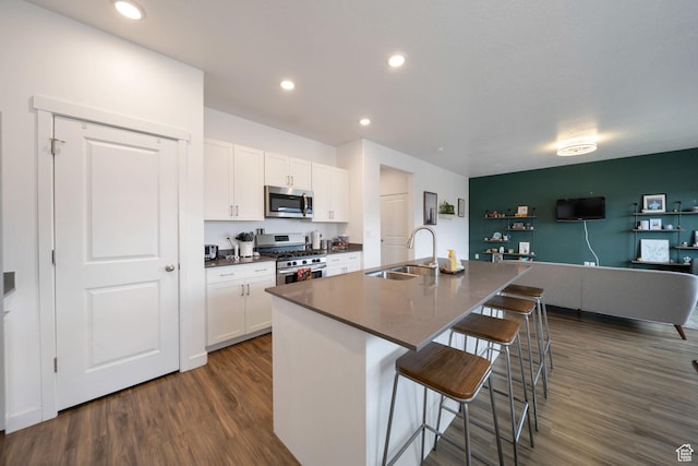 14837 S Messi St, Herriman, UT 84096 - kitchen featuring stainless steel appliances, dark countertops, dark wood-style flooring, white cabinets, and a kitchen bar