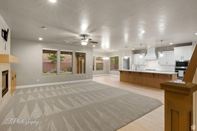 2762 E Hazel Dr, St George, UT 84790 - unfurnished living room with a tiled fireplace, a ceiling fan, recessed lighting, and a textured ceiling