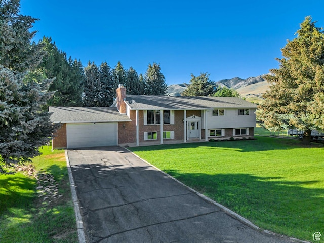 4918 E 2800 N, Eden, UT 84310 - split foyer home featuring a front lawn, asphalt driveway, a chimney, and an attached garage