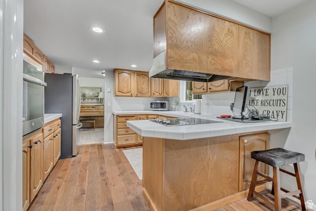 4918 E 2800 N, Eden, UT 84310 - kitchen featuring stainless steel appliances, a peninsula, tile countertops, light wood-type flooring, and backsplash