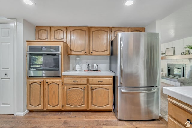 4918 E 2800 N, Eden, UT 84310 - kitchen with appliances with stainless steel finishes, tile countertops, light wood-style floors, a brick fireplace, and recessed lighting