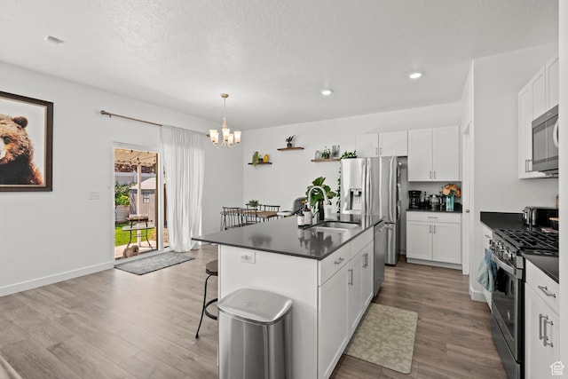 1017 S Red Cliff Dr, Santaquin, UT 84655 - kitchen with appliances with stainless steel finishes, dark countertops, a chandelier, wood finished floors, and recessed lighting