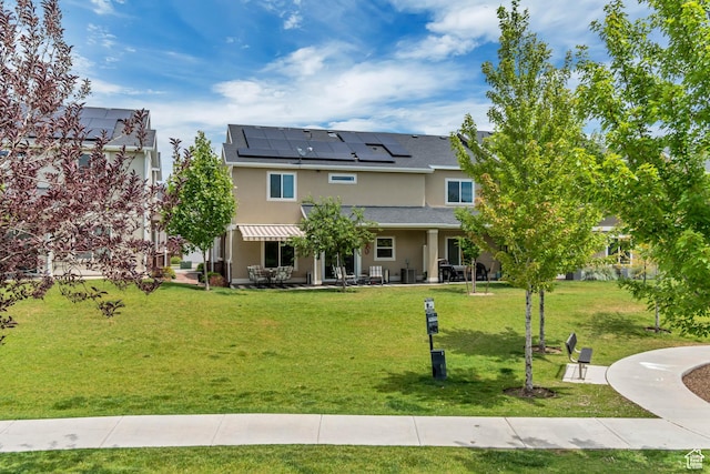 11874 S Rushmore Park Ln W, Herriman, UT 84096 - back of house featuring roof mounted solar panels, stucco siding, a lawn, and a patio area