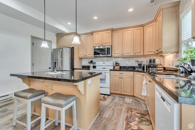 11874 S Rushmore Park Ln W, Herriman, UT 84096 - kitchen with stainless steel appliances, light brown cabinets, a breakfast bar area, light wood finished floors, and backsplash