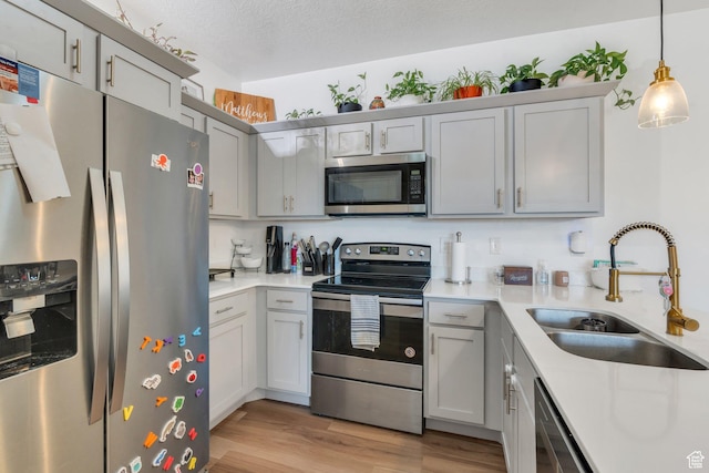 1831 W Newcastle Ln Unit 101, Saratoga Springs, UT 84045 - kitchen with appliances with stainless steel finishes, light wood finished floors, light countertops, decorative light fixtures, and gray cabinetry
