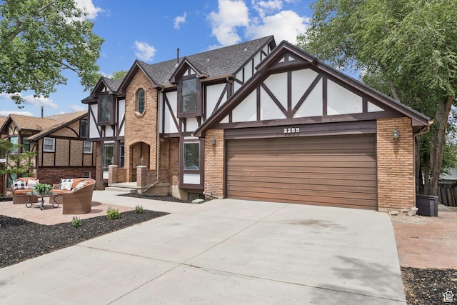 2255 E Camino Way Way S, Cottonwood Heights, UT 84121 - tudor-style house featuring a garage, driveway, outdoor lounge area, and brick siding